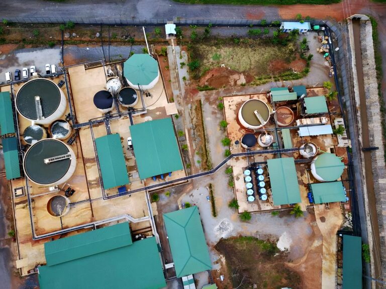 Aerial view of a wastewater treatment plant with green-roofed buildings and circular tanks